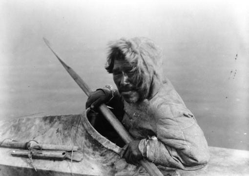 a man in a fur jacket sitting in a canoe