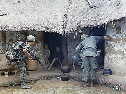 soldiers peer into a hut with children