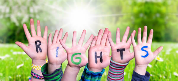 children’s hands raised with the word “rights” written across the palms