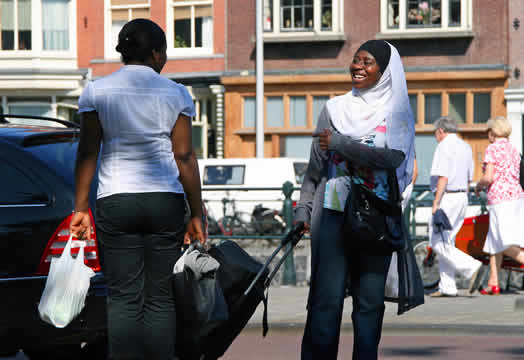 two women holding bags smiling in a busy street