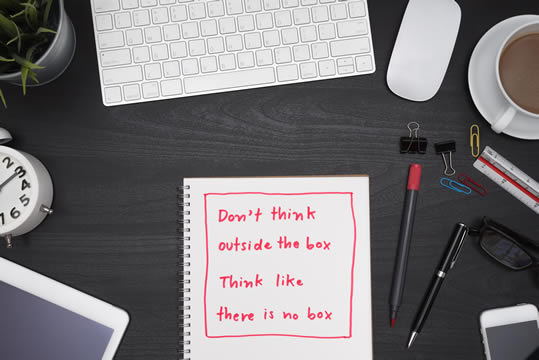 desk with a note: "Don't think outside the box; think like there is no box"