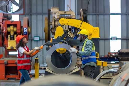 two workers in safety gear examining an industrial machine