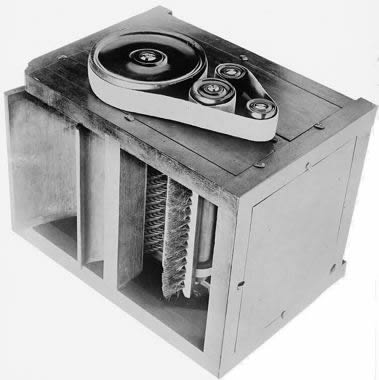 photo of machinery with tape going through reels at the top and a brush below