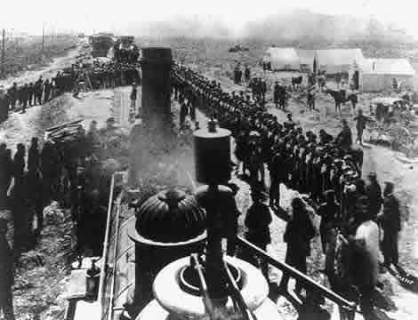 photo of train engine arriving into station with lines of people greeting it