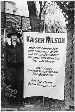 woman holding a protest sign to “Kaiser Wilson,” asking how he can fight for the right to self-government of poor Germans when American women do not have the right to self-government