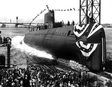 a submarine heads out to sea while a crowd looks on