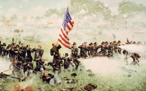 In this wide landscape painting, a long line of Union soldiers in dark blue uniforms kneels and stands in a grassy field while firing their rifles into a thick bank of white smoke. A central soldier stands tall and holds a large American flag aloft, while several fallen men lie in the grass in the foreground, and a distant house is visible through the haze of battle.