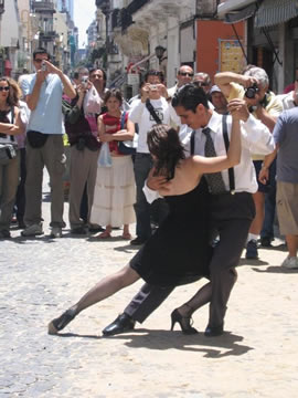 a couple dances in the street while others photograph them