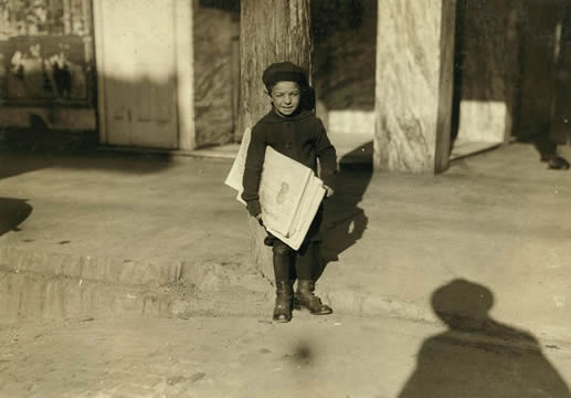 a child holds a stack of newspapers