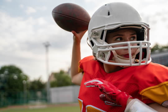 photograph of a girl in full football gear, getting ready to pass the ball