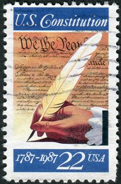 a US stamp celebrating the centennial of the US Constitution; shows a hand holding a pen quill against a background of the Constitution