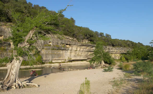 people in the river with sand on one bank and rocks on the other