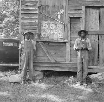 two men standing outside a wooden building