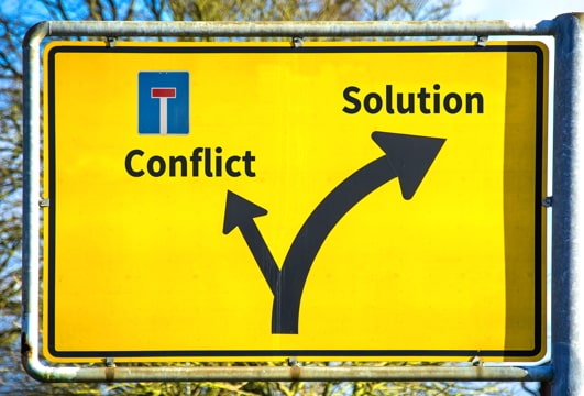 road sign showing fork, one dead-end direction labeled “conflict” and the other direction labeled “solution”