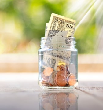 a jar full of coins and one dollar bills