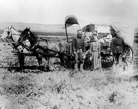 photograph of a family alongside a horse-drawn wagon