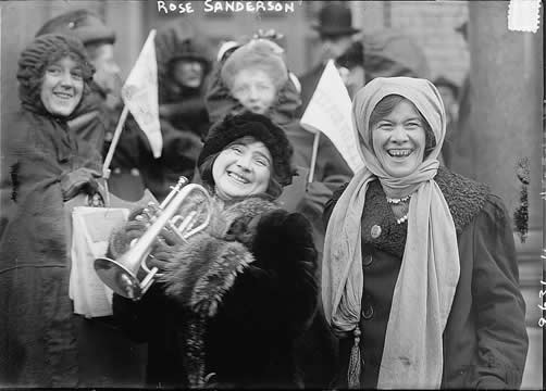 women laughing at a protest, one with a trumpet