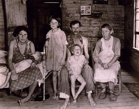 photograph of poor parents, a grandmother, and three small children living in a shack
