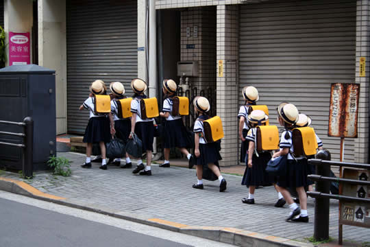 schoolchildren walking on a street with bags on their backs