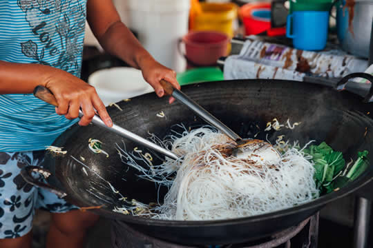 someone sitting in a canoe by a dock with pots of food