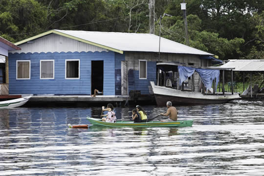people in a canoe rowing to a house on the water