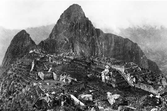 black and white photograph of ruins on a mountain peak