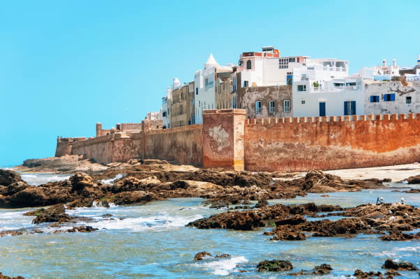 rocky beach next to a walled city