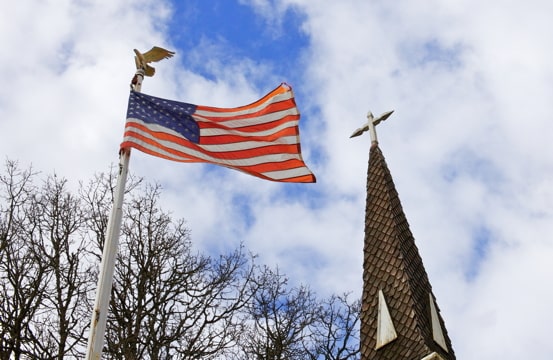 photo of an American flag alongside a church steeple