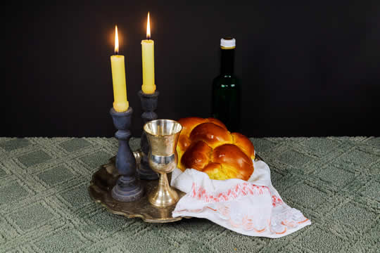 Photograph of candles, braided bread, and silver goblet
