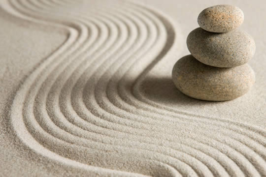 photograph of curved lines in sand and stacked stones