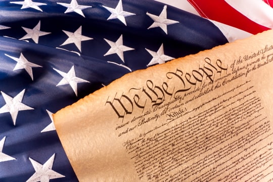 the U.S. Constitution against a backdrop of the U.S. flag