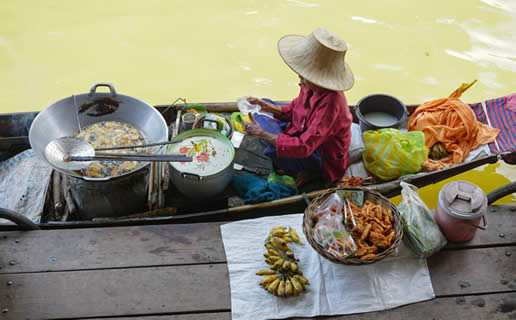 someone sitting in a canoe by a dock with pots of food