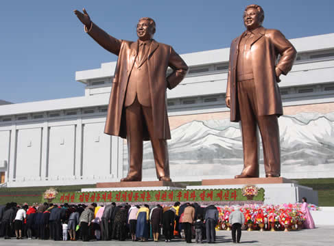 people bowing to two large statues