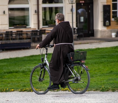 a friar riding a bicycle on a sidewalk