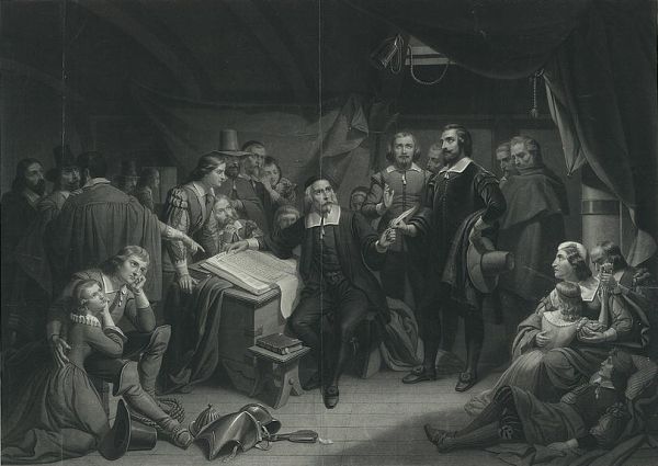 A group of solemn Pilgrims is gathered inside what appears to be a ship's cabin or a simple dwelling. Several figures are seated or standing around a table with an open book, while others, including women and children, appear weary and rest in the foreground and background.