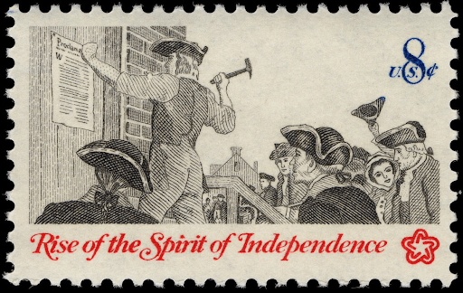The image is a postage stamp featuring a black and white illustration of a man posting a document on a wall as a crowd of colonists watches. Below the illustration, in red text, are the words "Rise of the Spirit of Independence," and the stamp's value of "8 U.S. ¢" is in the top right corner.