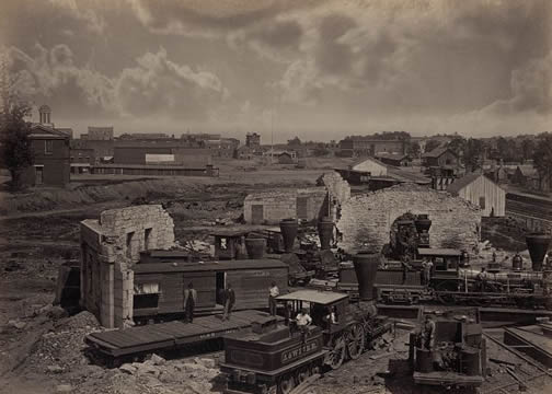 old photograph showing the shell of a building and a railroad engine off the tracks