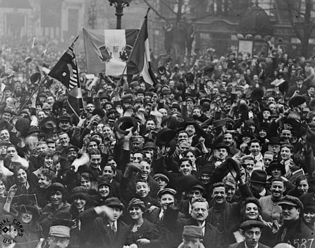 historic photo of a crowd of people waving flags celebrating the end of the war