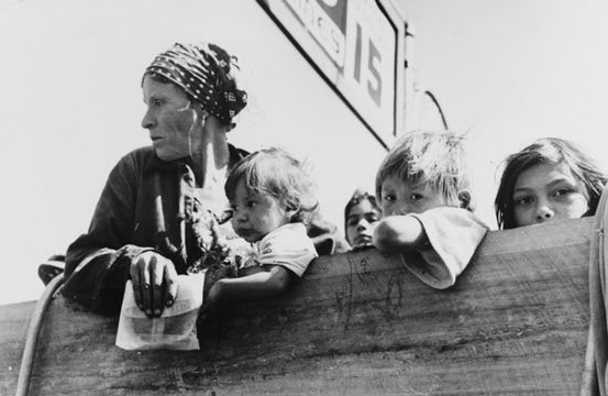 A mother and four children look sadly over the side of a pickup truck