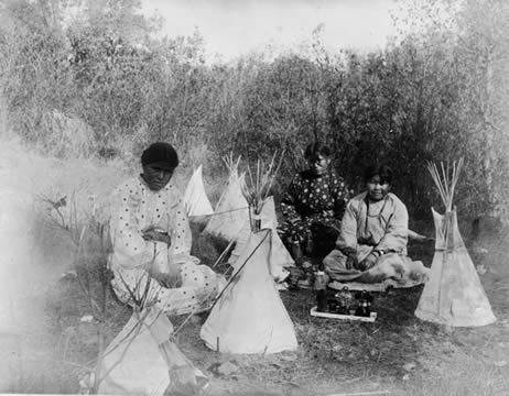 photograph of three young Indigenous girls playing with toy teepees