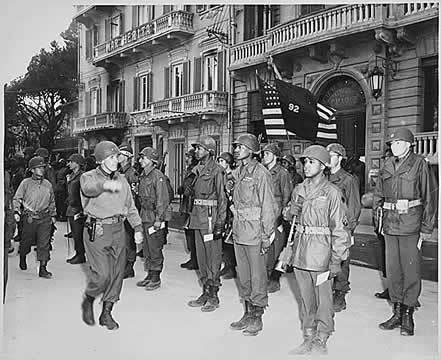 A black and white photograph of a U.S. major general inspects his troops during a decoration (medal) ceremony in Italy