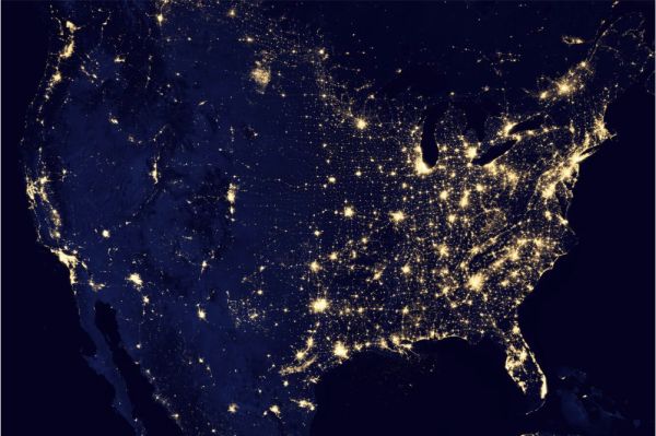 A nighttime visual of the United States with colorful lights in parts of the country where people live.