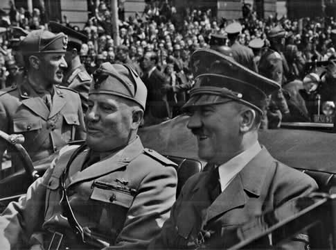 two men ride in an open car surrounded by hundreds of people
