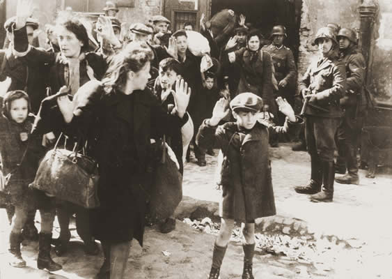 people stand in the street with their hands raised with soldiers looking on