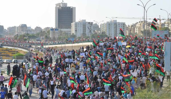 A large crowd marches through a city street while waving Libyan flags during an anti-Qaddafi protest in Benghazi, Libya.