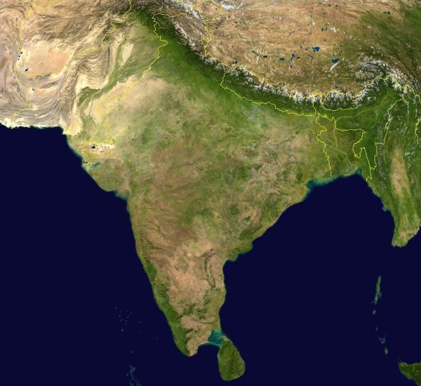 Satellite image of the Indian subcontinent showing India and surrounding countries, with the Himalayas across the north, greener river plains in the north and east, and drier regions to the west.